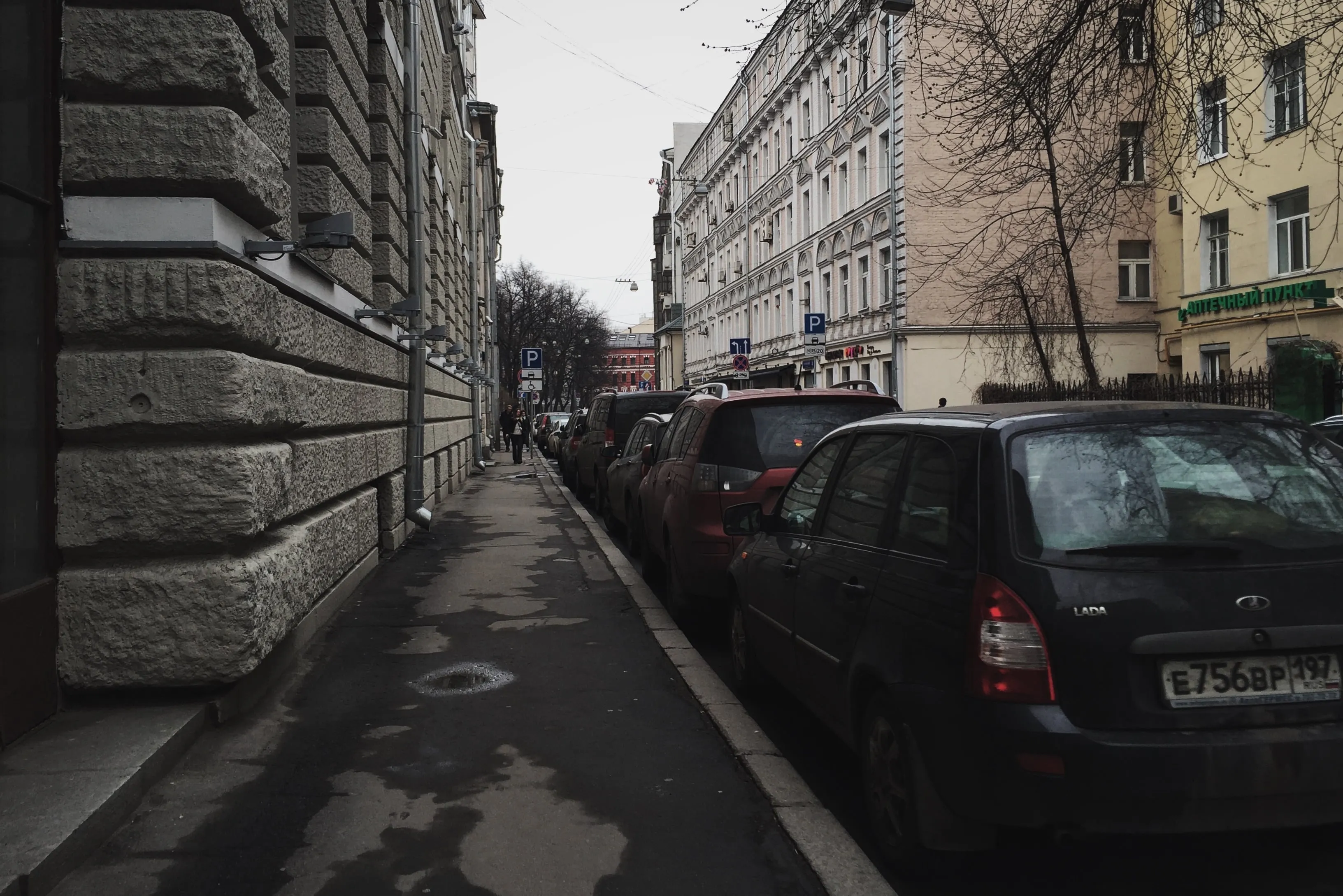 Большой Патриарший переулок: тротуар у здания из рустованного камня и ряд припаркованных машин